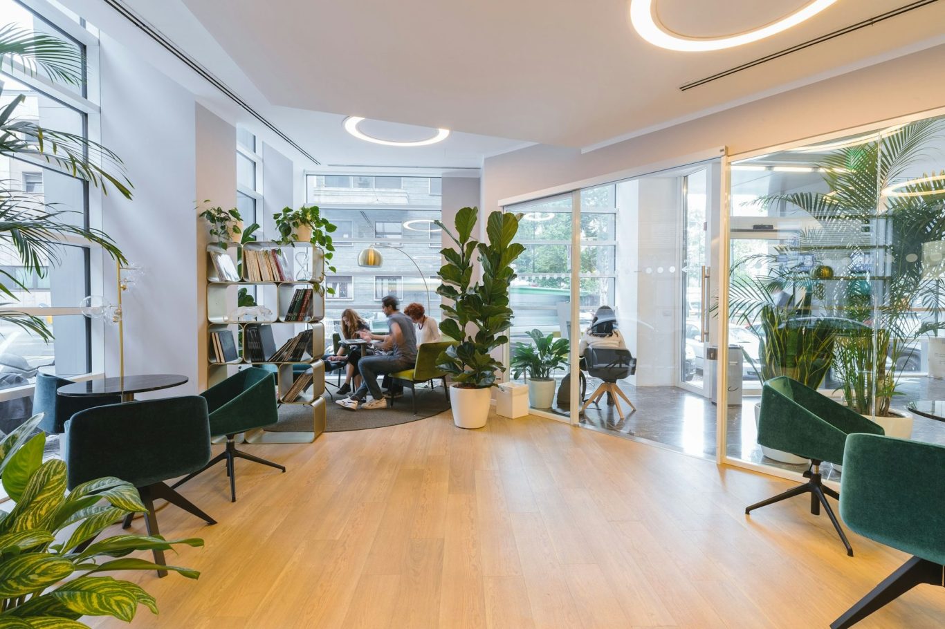 Moderne Lounge mit Pflanzen und Sitzbereichen, Gruppen von Menschen in Konversation.